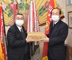 本美校長（左）にりんごジュースを手渡す川上専務（右）