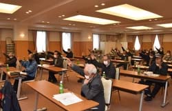 挙手で議案を承認する花き部会員