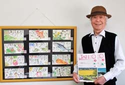 広報誌に掲載された絵手紙をバックに笑顔を見せる中島さん