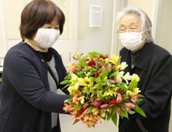 購入したアルストロメリアを手に笑顔を浮かべる女性部員