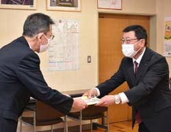 松下校長（左）に教材を手渡す丸山常務（右）