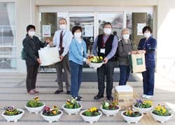 山﨑施設長（右）と高山理事長（右から3番目）、土屋常務（左から2番目）に鉢花と清拭布を手渡す部員