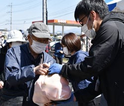 来場者に柑橘類袋詰を手渡すJA職員（右）と受け取る来場者（左）