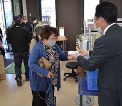 支所入口で記念品を受け取る来所者