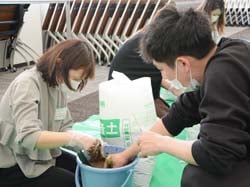 指導員に教わりながら稲を植える学生