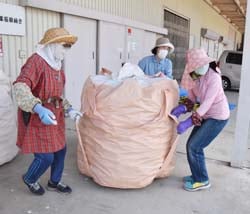 アルミ缶の入った袋をトラックまで運ぶ女性部員（長野市若穂、6月1日）