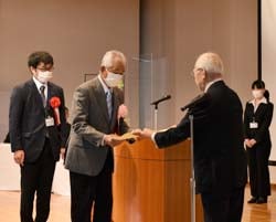 功績を称え表彰状を渡す河崎審査委員長（左から3人目）と金賞の高山さん（左から2人目）