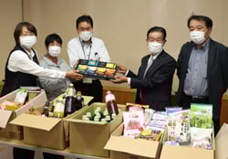 集めた食料を渡す林所長ら（左から3人目） 