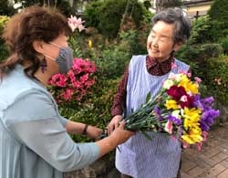 女性部役員から花束を受け取る部員（右）