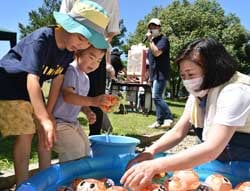 ぼんぼんつかみを楽しむ来場者（左）とJA職員（右）