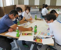 和やかな雰囲気の中でお互いの意見を書き込む職員たち