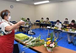 久保会長に教わって花を生ける女性部員