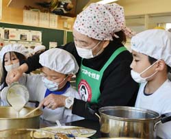 児童（中央）に豆腐の作り方を手ほどきする女性部員（右から2人目）