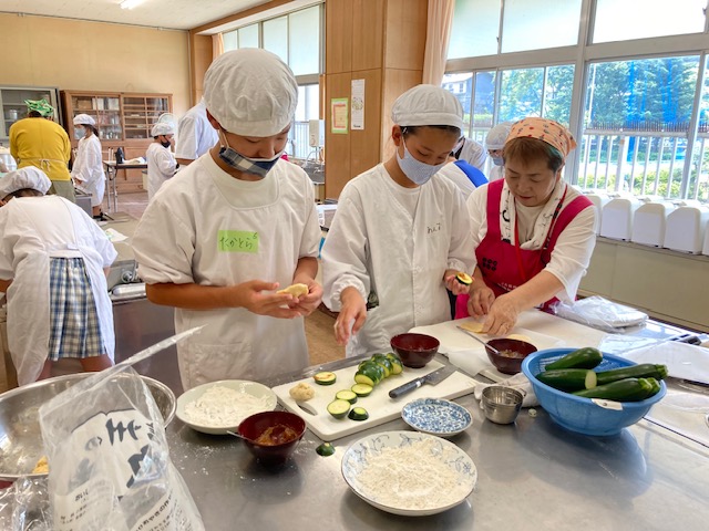 女性部員からおやき作りを学ぶ児童たち