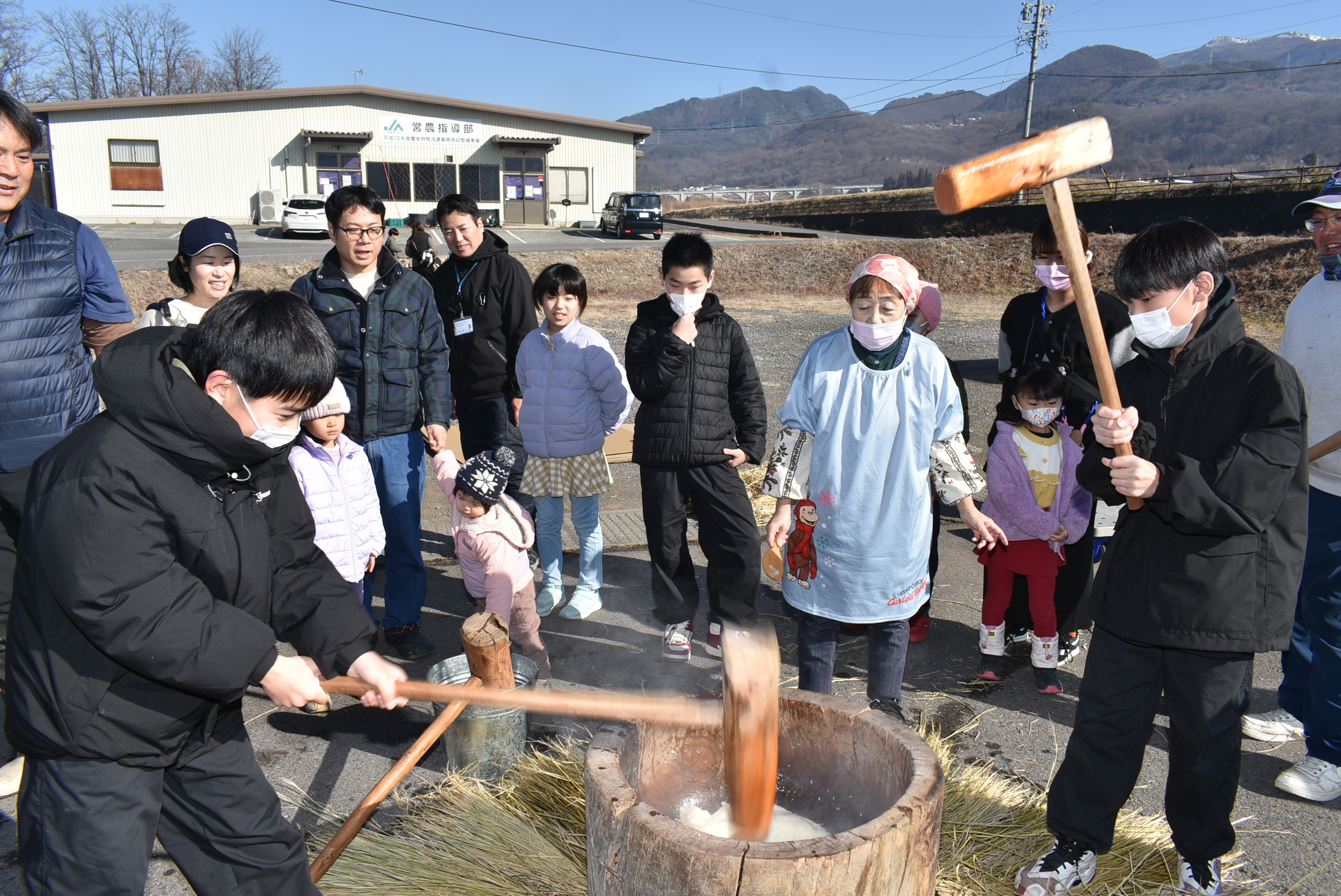 杵を使って餅をつく子供たち