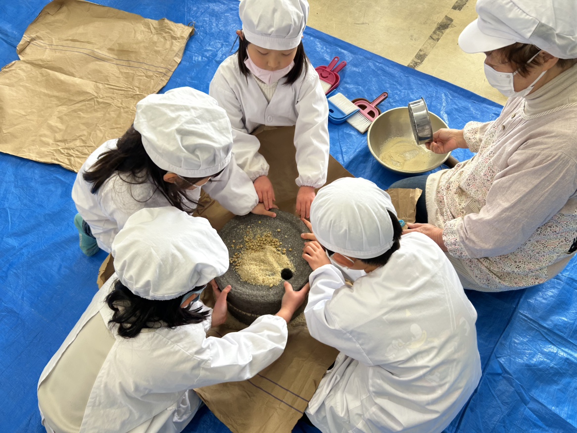 石臼で大豆を挽く児童ら